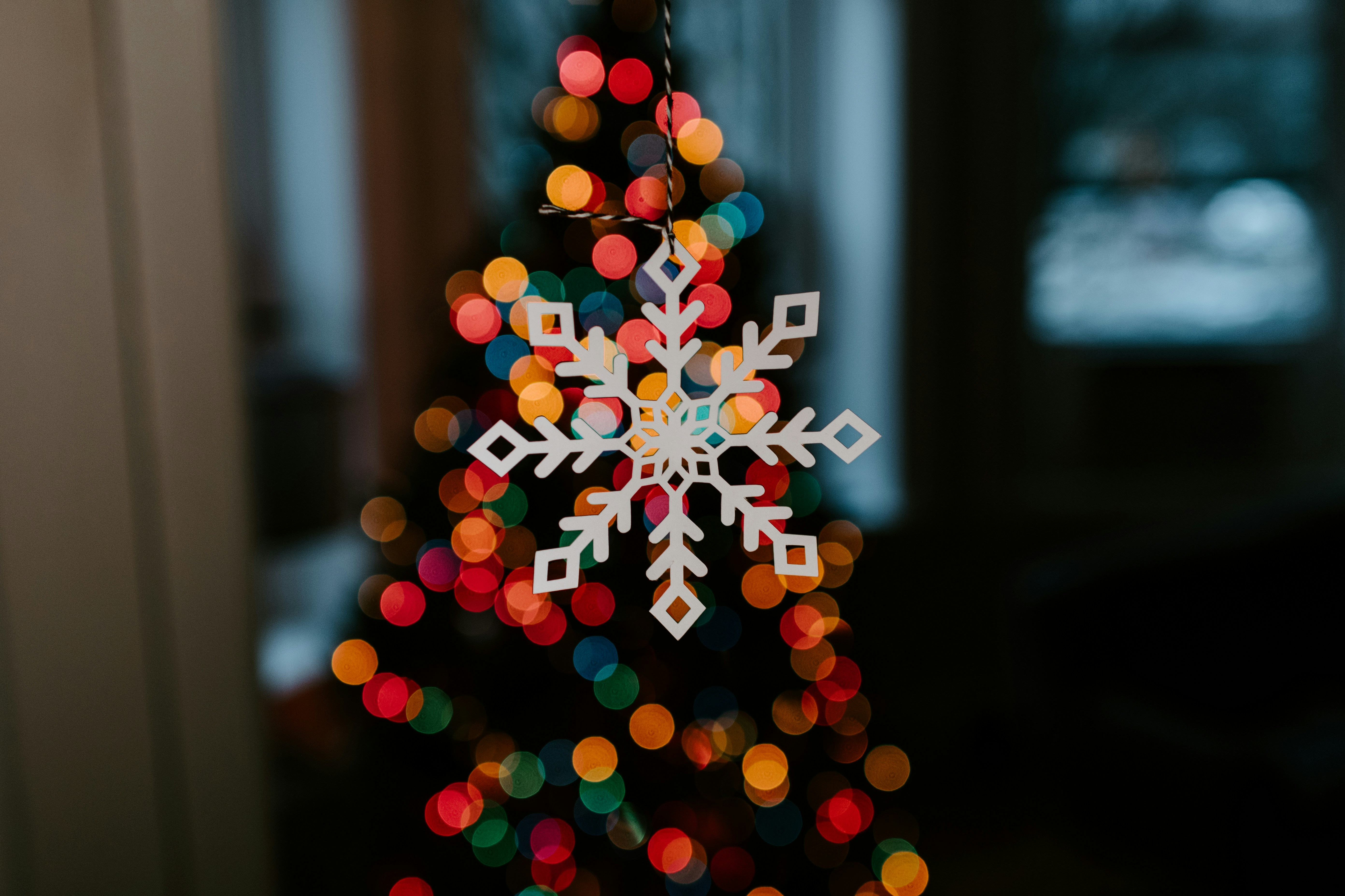 A white snowflake in front of some festive lights