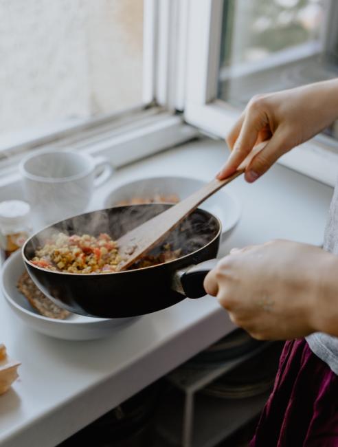 Person cooking a meal using a pan