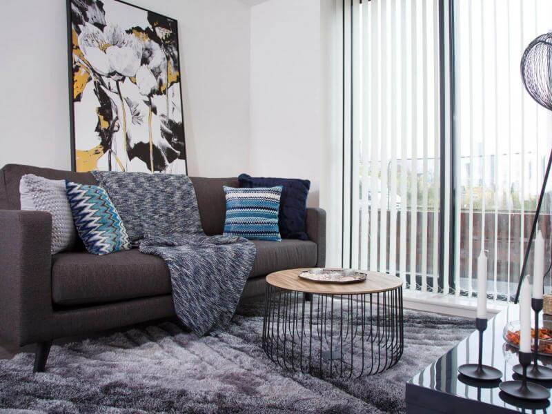 Photo of the living room at The Clockworks with a grey sofa and large window