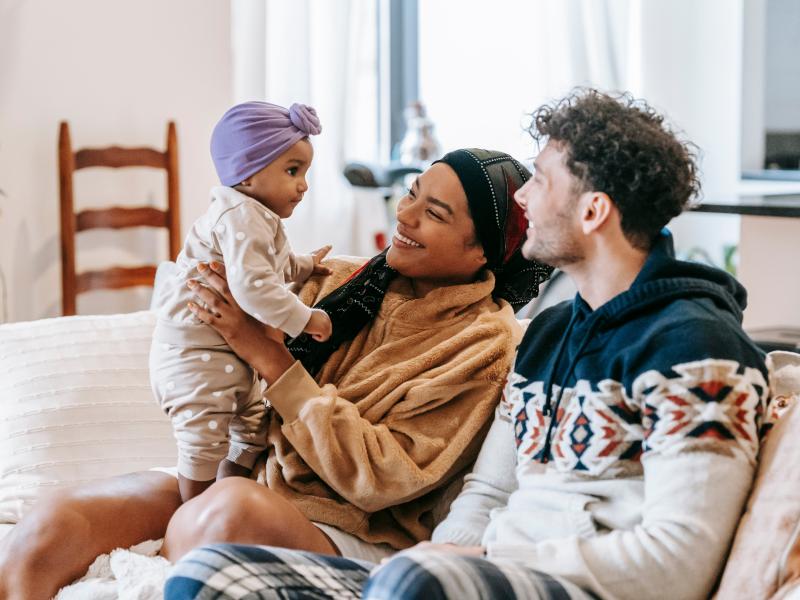 Mum dad and baby in lounge playing