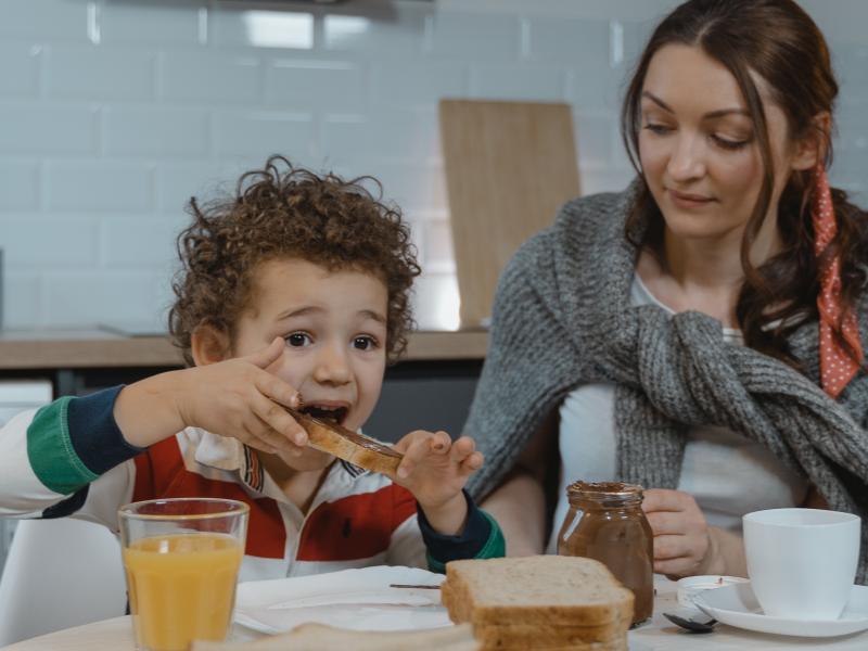 An image of a young woman and a small boy eating breakfast together. 
