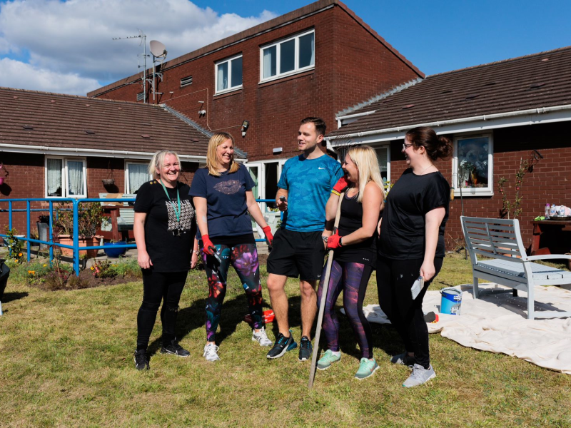 A picture containing volunteers standing in a garden. 