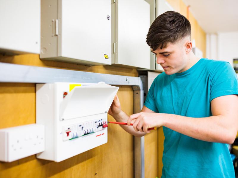 An image of a young male One Manchester colleague fixing a fuse box