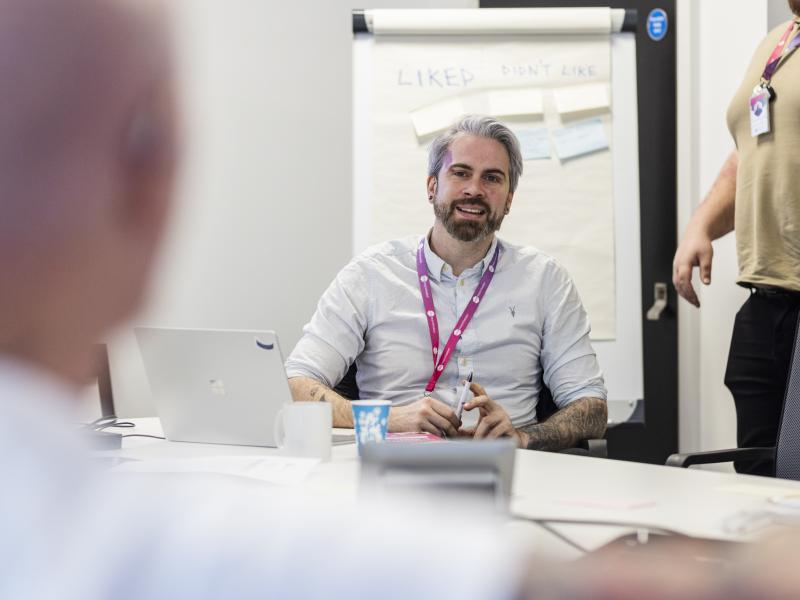 Man sat in chair having a discussion with people.