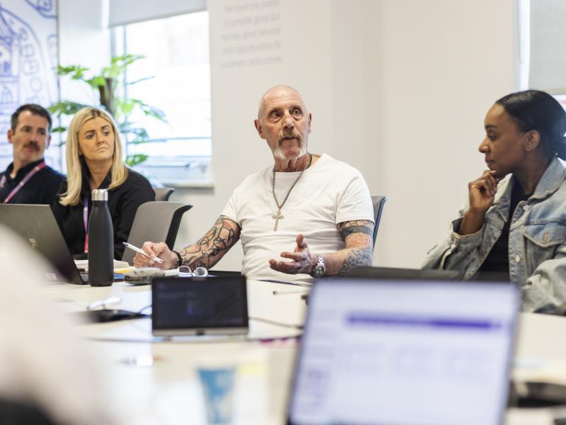 One Manchester Colleague in discussion at a table with other people.
