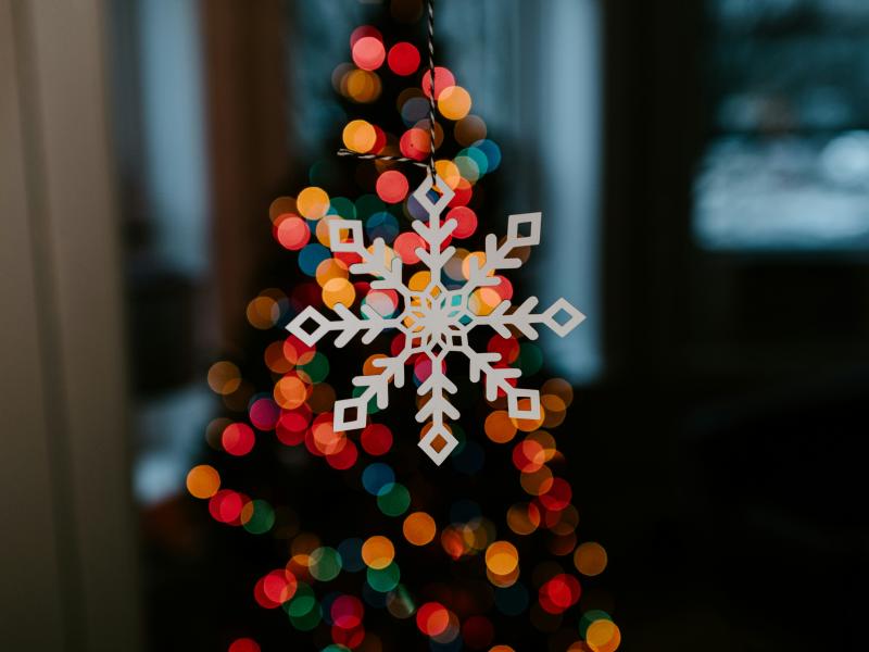 A white snowflake in front of some festive lights