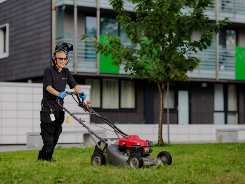 One Manchester colleague cutting grass with a red lawn mower.