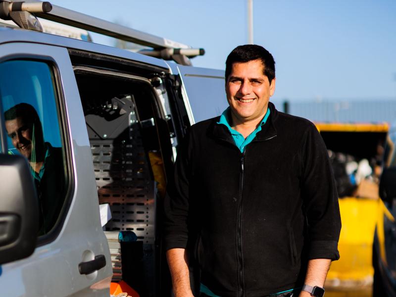 An image of a male One Manchester colleague smiling stood next to a work van