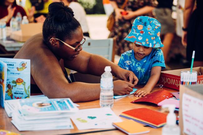 A woman and small child doing crafts at the Manchester Caribbean Carnival
