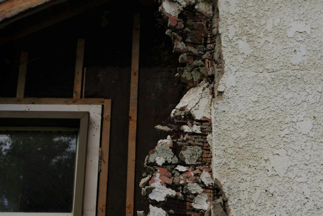 A property that has potential structural asbestos. The image shows the wall being taken down with the material coming from within the wall. 